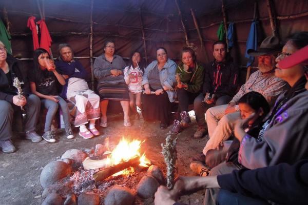 An IPS delegation meets with partners around a fire.