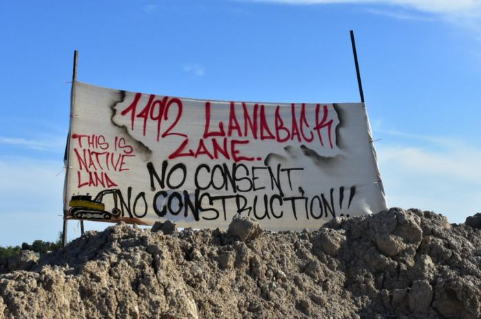 Large banner on construction site reading, '1492 Landback Lane.  No Consent; No Construction.'