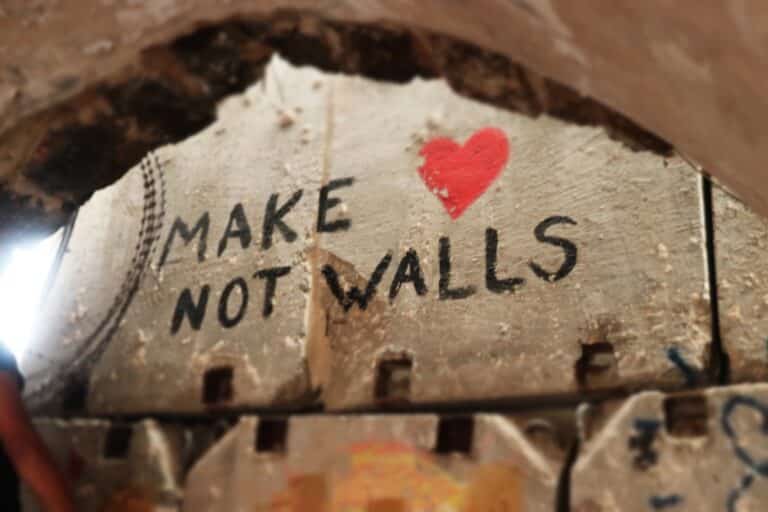 A painting on the separation wall that reads "Make [heart] not walls"