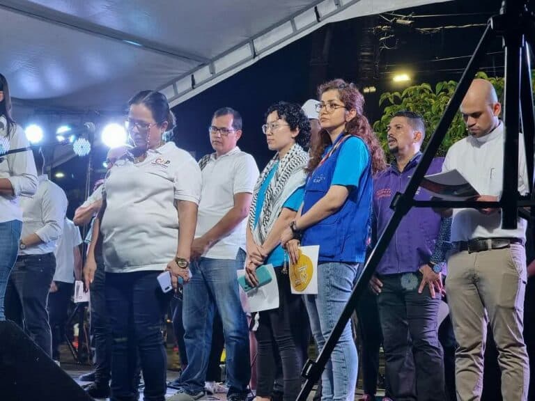 CPT members stand on stage, wearing blue vests, preparing to speak during the event for 25 November, the Day to Eliminate Violence Against Women, in Barrancabermeja, Colombia.