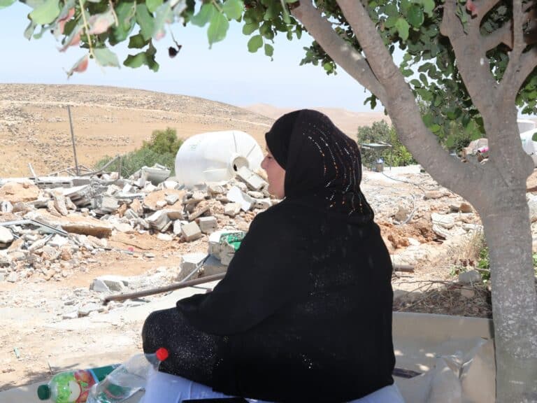 A woman looks on at rubble
