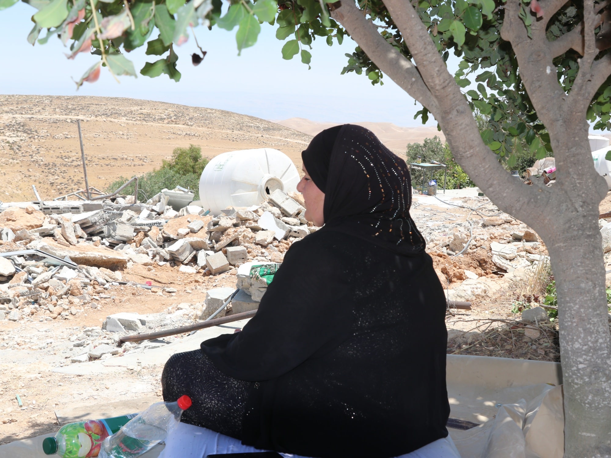 A woman looks on at rubble