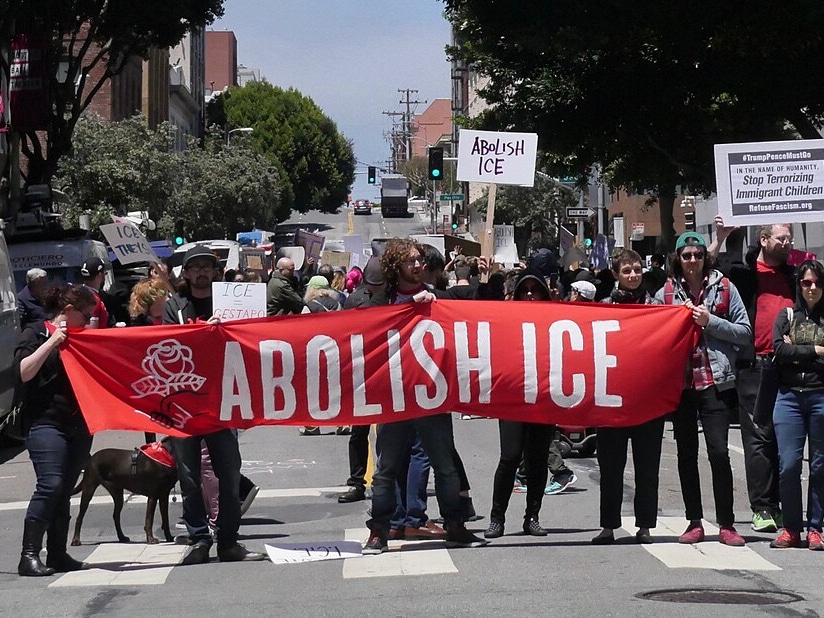 People hold a banner reading "Abolish ICE"