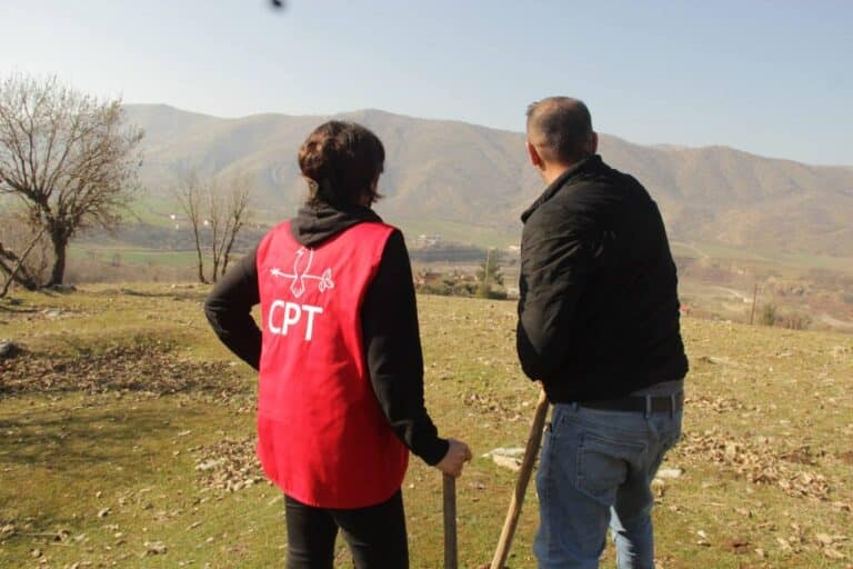 a cpter wearing a red vest looks into the horizon with a man wearing a black jacket