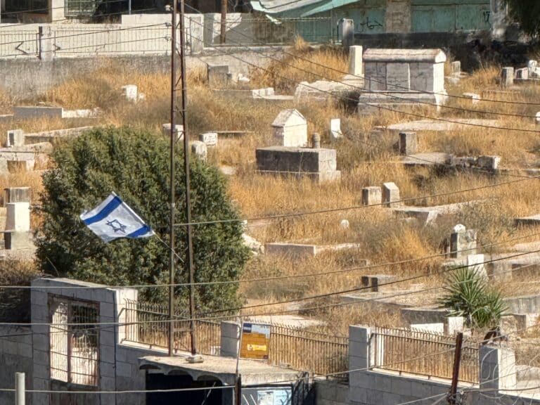 A fence bearing an Israeli flag blocking the entrance of a cemetery