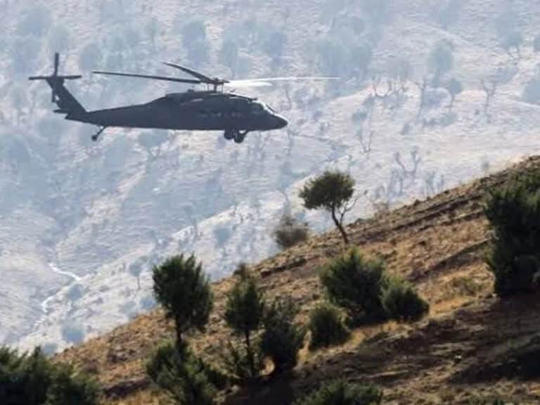 A helicopter hovers over a hillside