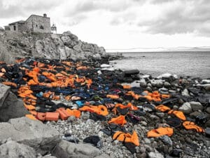 Lifejackets piled up on a coastline