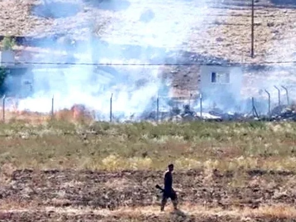 A man walks in front of smouldering land