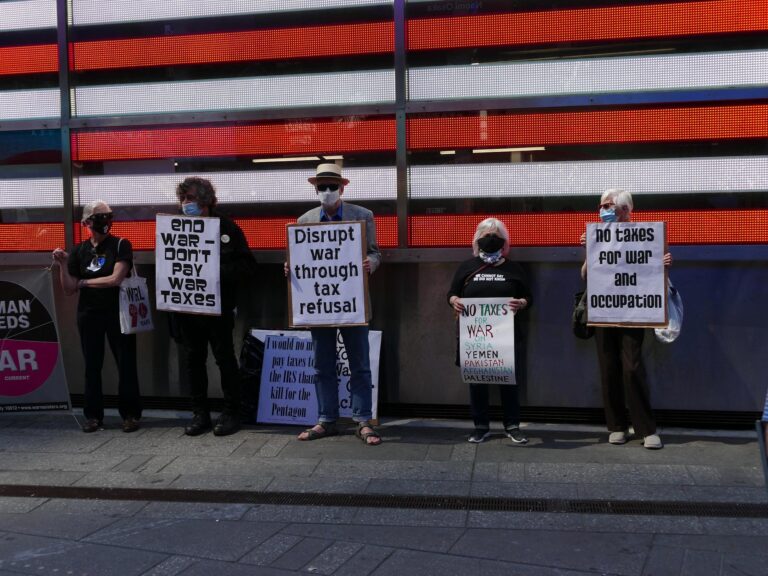 people stand with signs at a demonstration