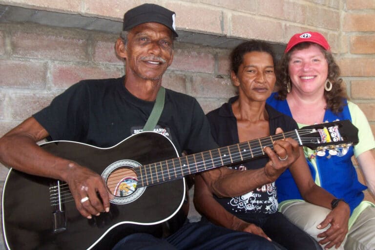 three people pose for portriat and one holding a guitar