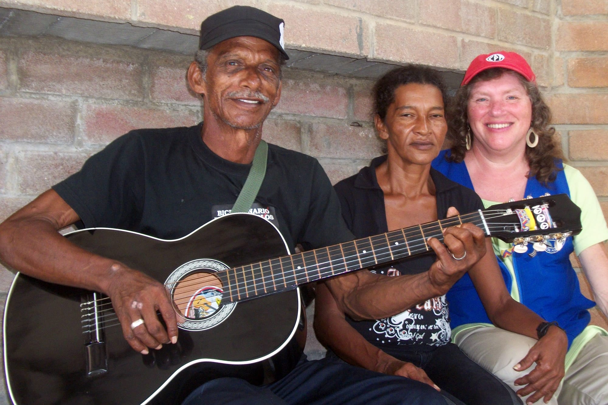 three people pose for portriat and one holding a guitar