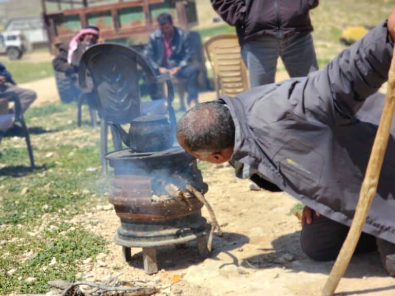 A man blowing on the embers of a stove