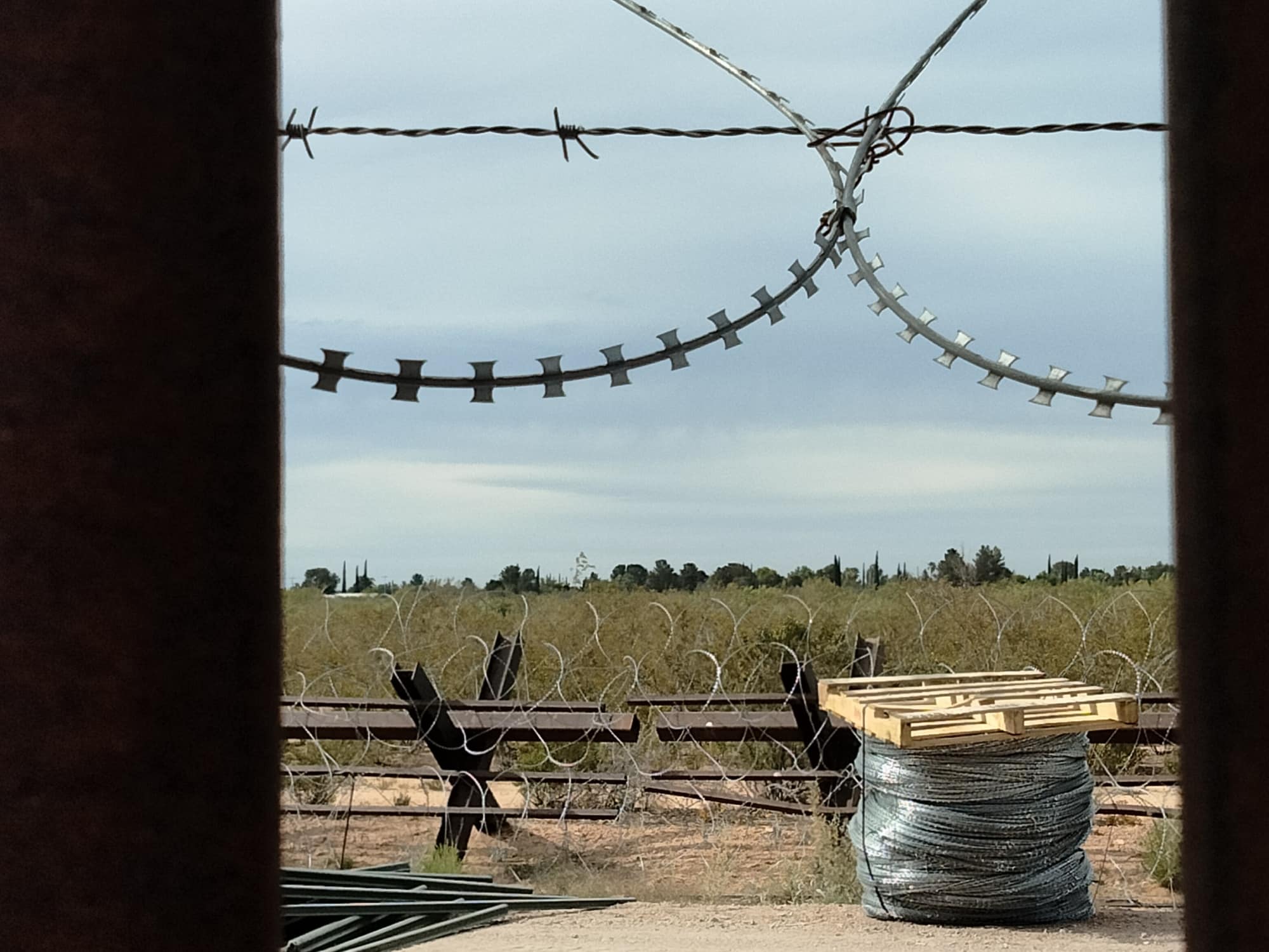 A border fence and a spool of razor wire
