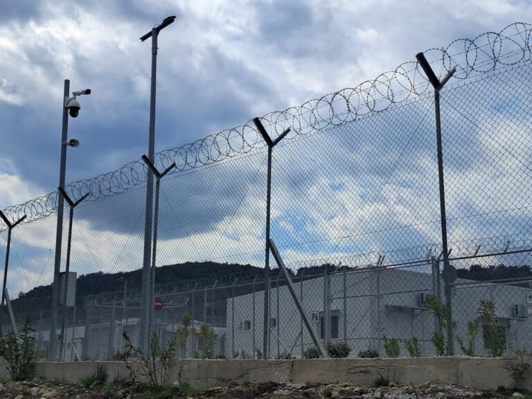 A barbed wire fence around a refugee camp