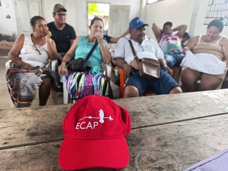 A cap on a table in the foreground of a meeting