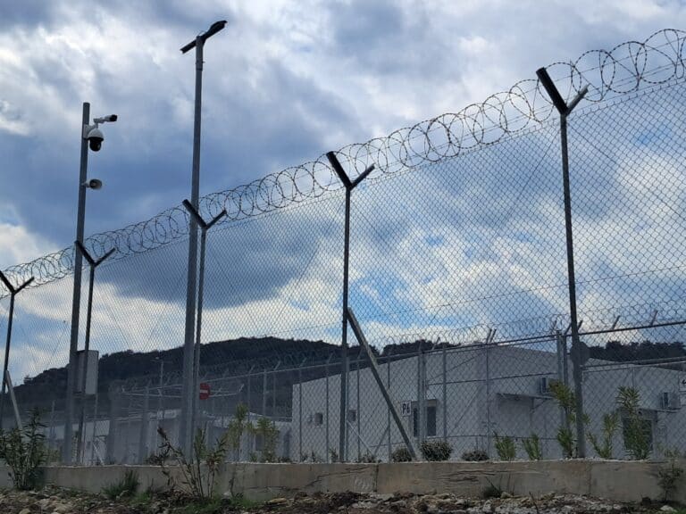 A barbed wire fence surrounding a refugee camp