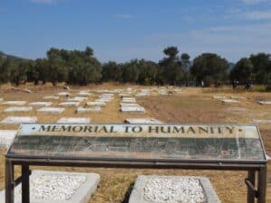 A sign reading "memorial to humanity" in the foreground of a graveyard