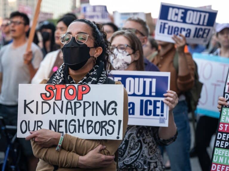 A woman holds a sign reading "Stop kidnapping our neighbors"