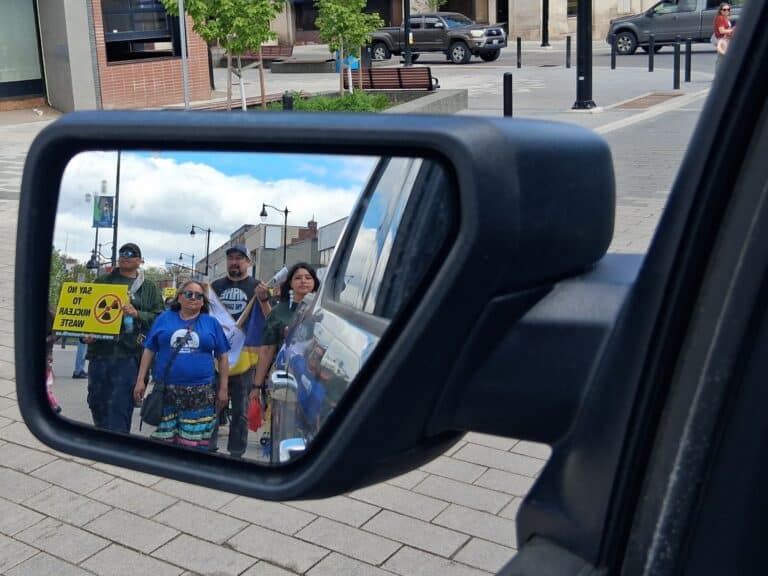A rearview mirror shows people marching