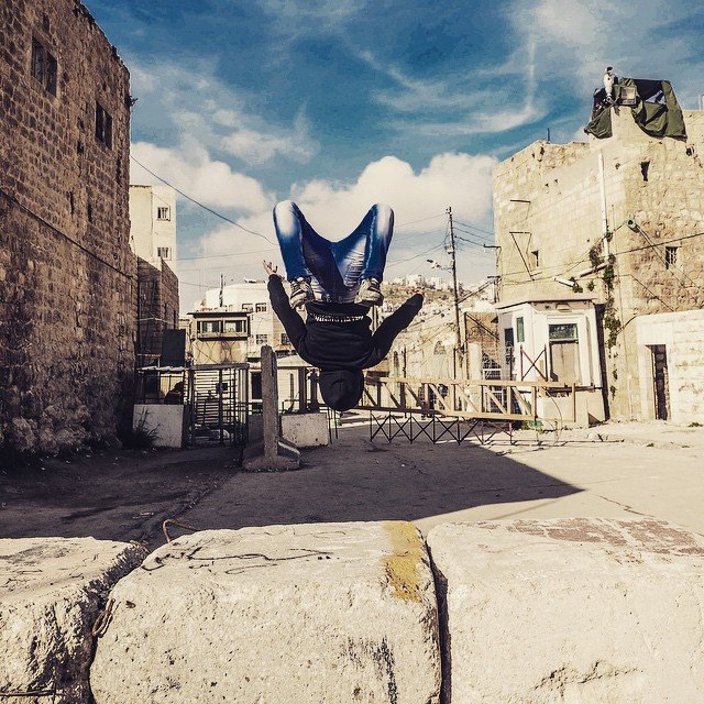 a Palestinian boy does a back-flip off a concrete 'security block' towards a checkpoint, whilst Israeli forces were preparing for an incursion into the Qitoun neighbourhood