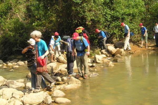 A Colombia delegation crosses water on a path of stones.