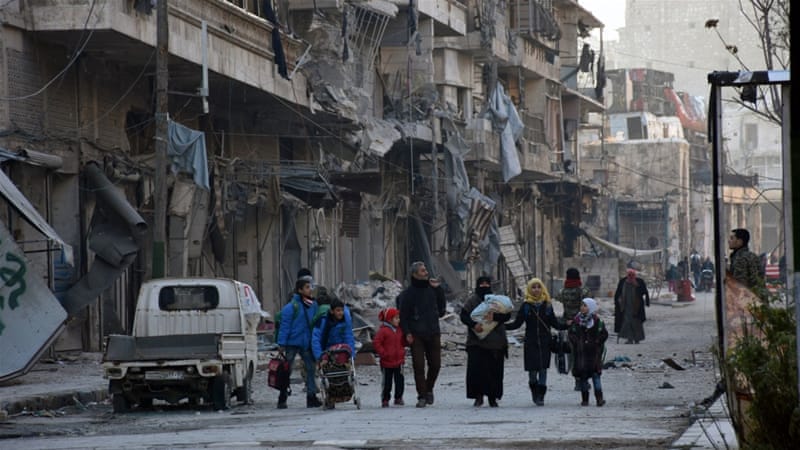 Family walking in Aleppo. The city is destroyed