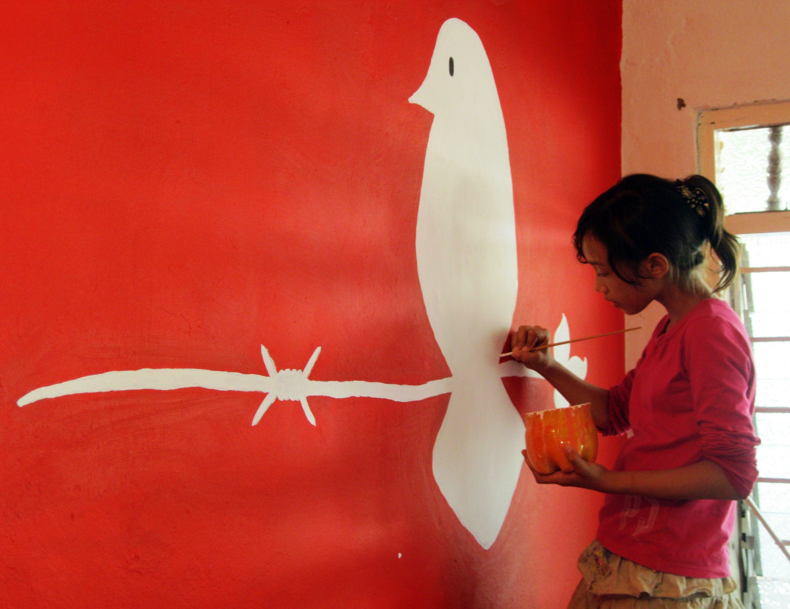 Artist painting CPT logo on wall of CPT Colombia office