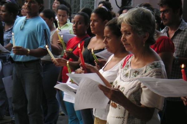 Women stand holding candles. 